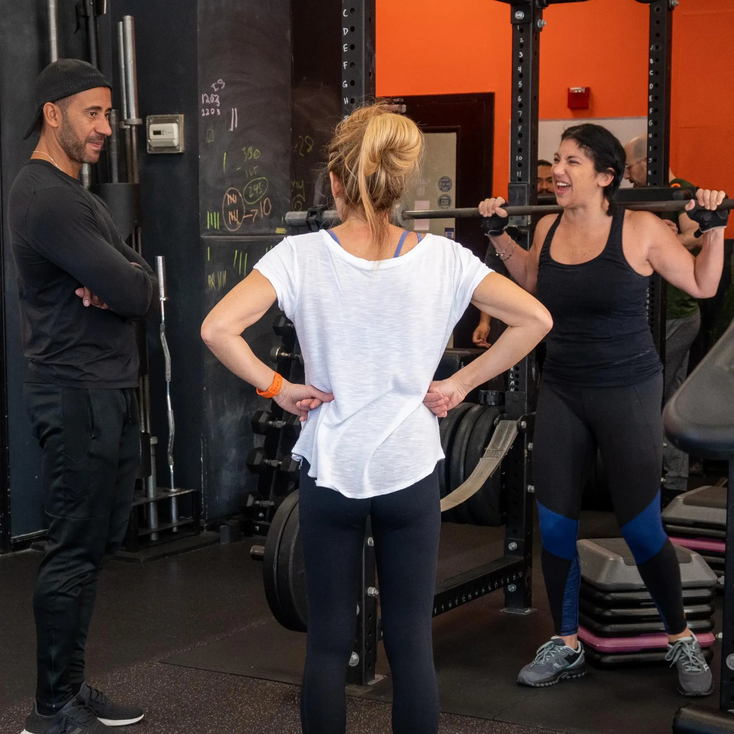 Two Kaeos coaches cueing a client through a barbell squat